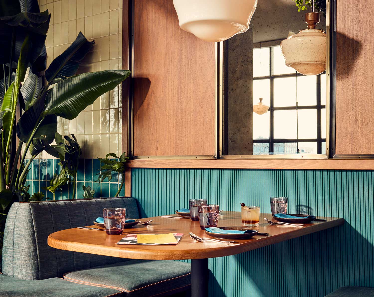 Seating booth set up for dining with a large leafy plant in the background