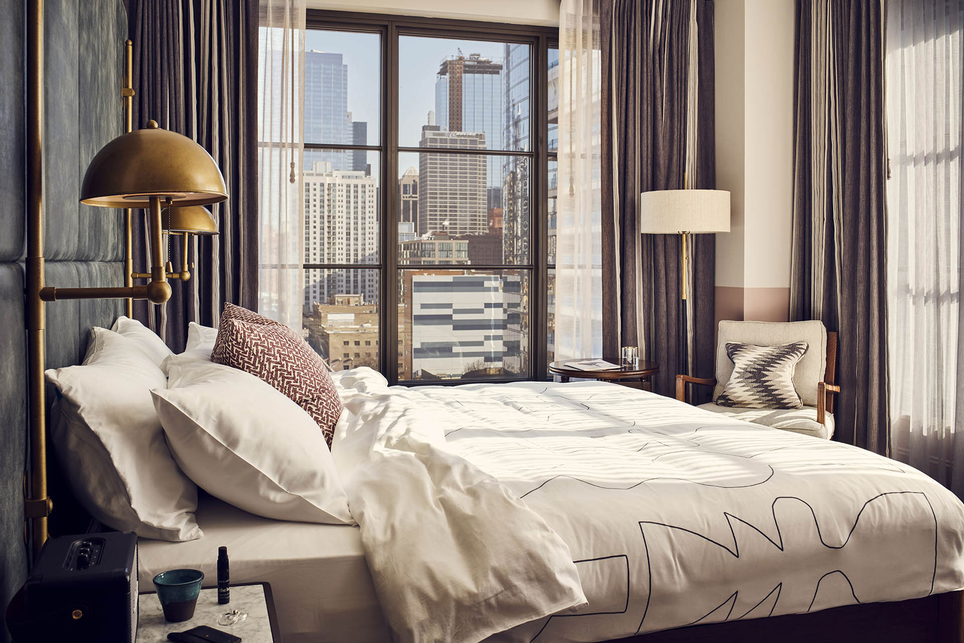 Sunlight streams onto the hotel bed, with a stunning view of Chicago outside