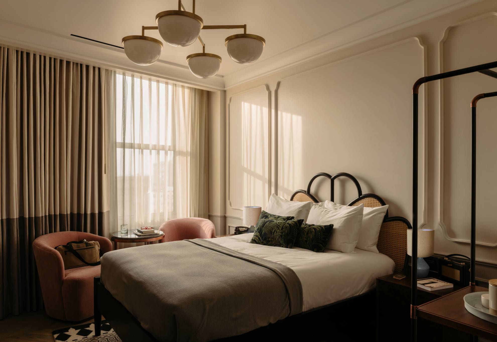 Cosy King room featuring a king-size bed, two soft pink velvet chairs next to a large window, and a table