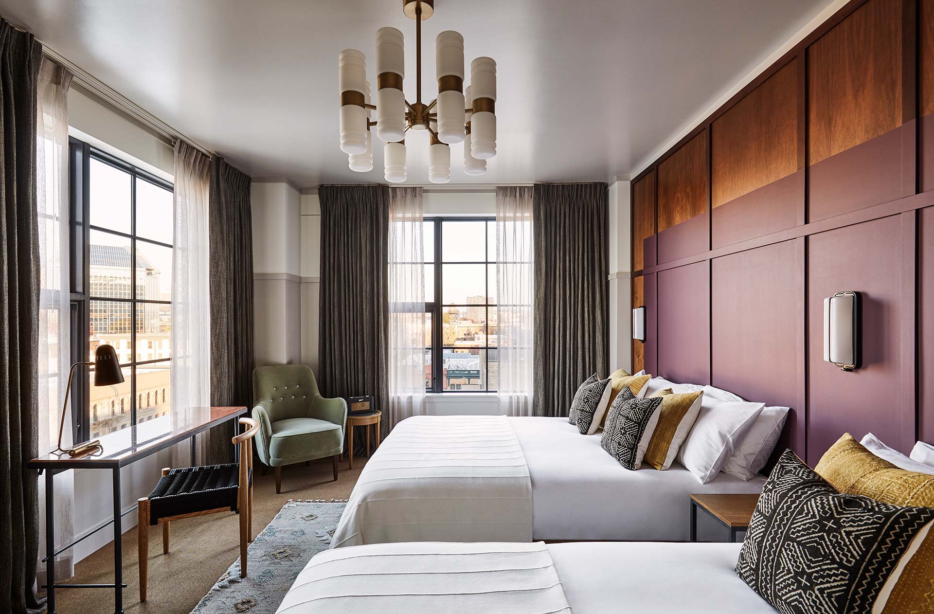 Two queen beds in a large hotel room, with windows on both the opposite and on the adjacent walls