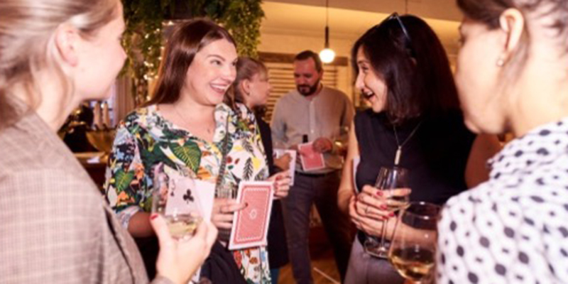 Revellers play a novelty card game at a party with drinks