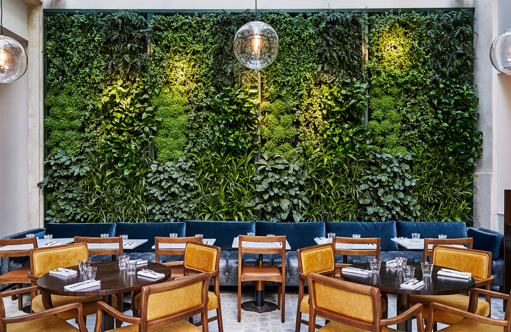 A wall of thick greenery behind restaurant seating