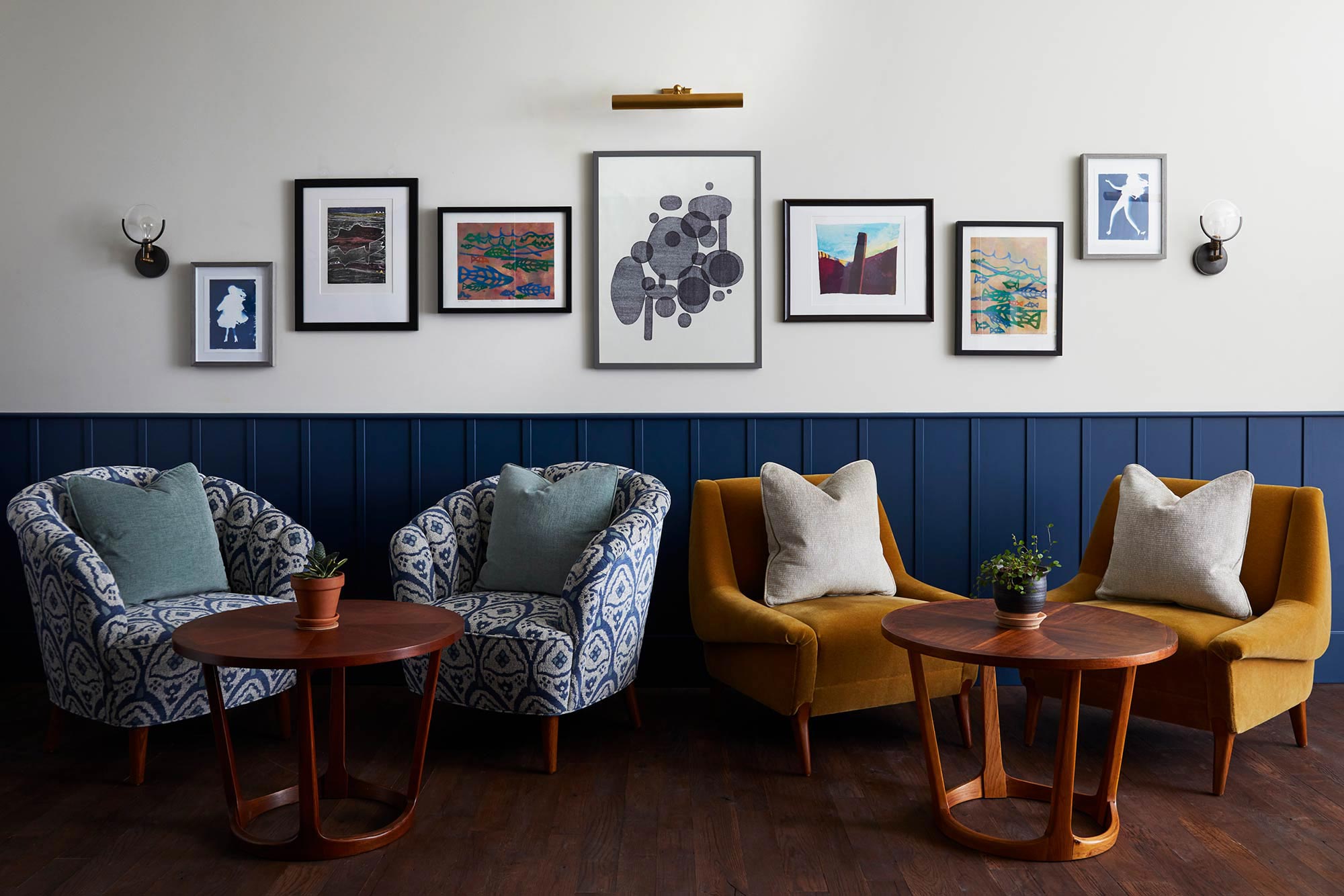 Two pairs of lounge seats with cushions below modern artwork