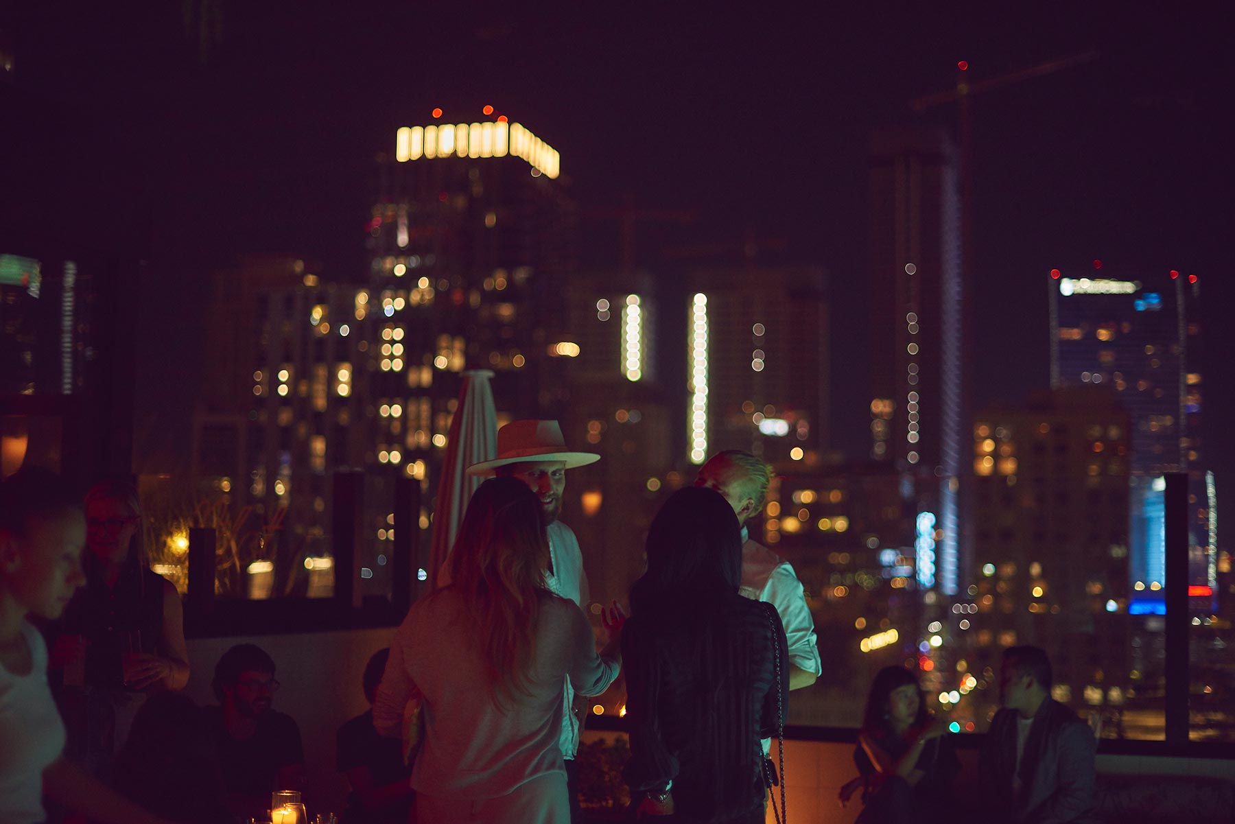 Guests enjoying a event on the rooftop at night, with the city lights behind them