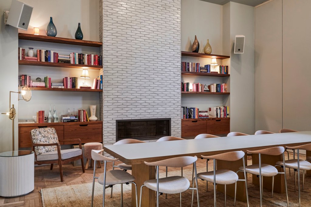 There is a fireplace in the middle of one wall, with book shelves either side, and then a long table with chairs around it
