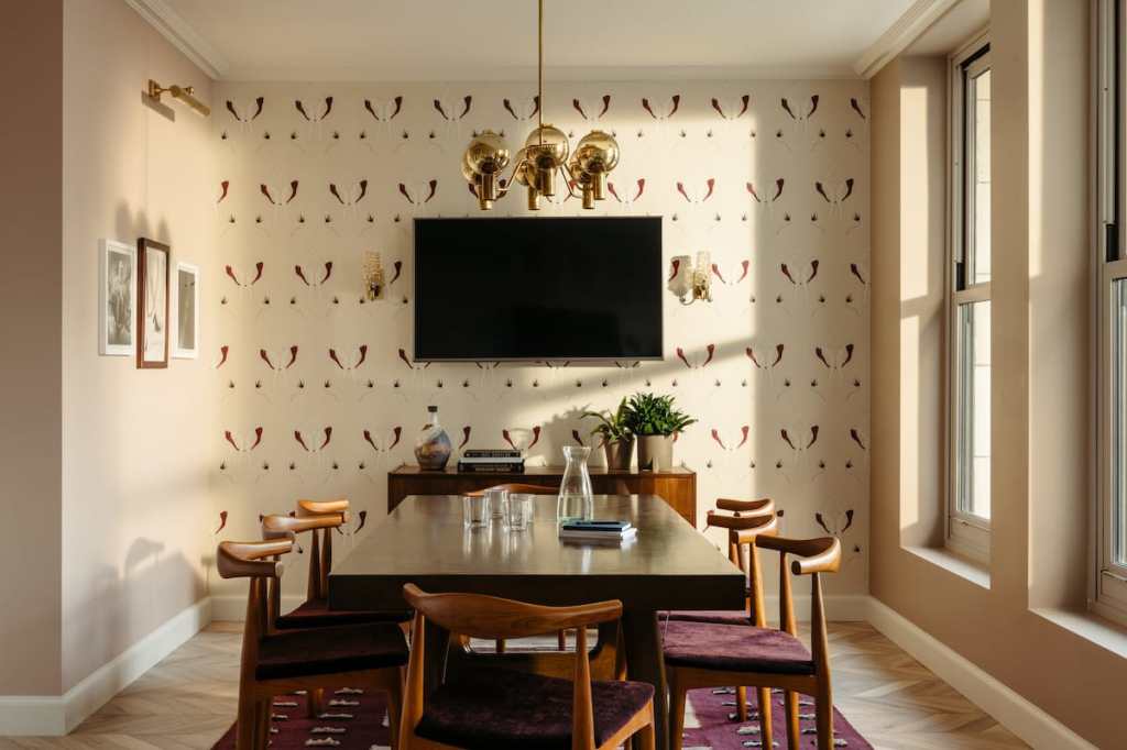 The meeting room has a table with eight chairs, and a large TV on the wall