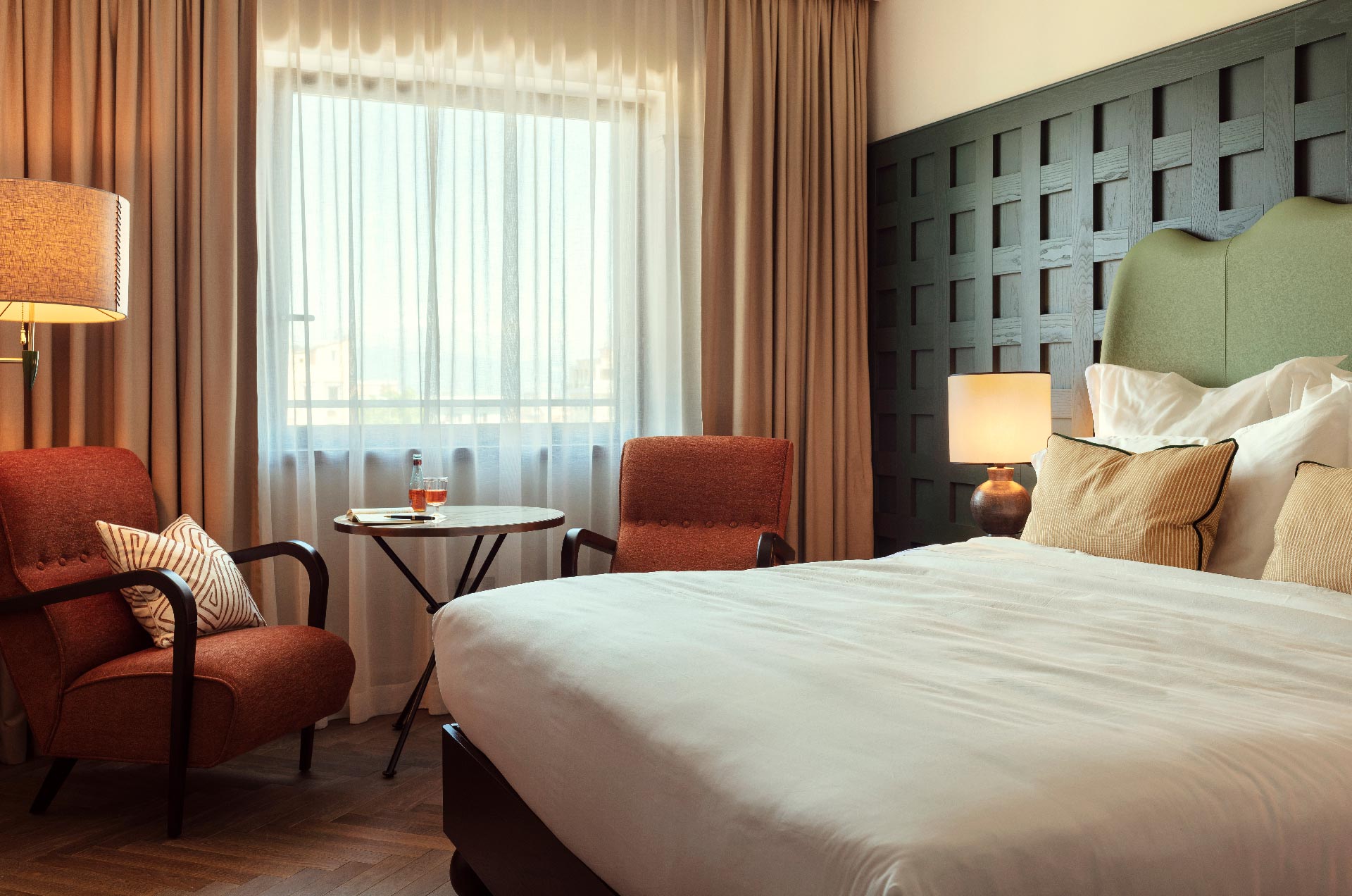Large king sized bed, with two armchairs beside a table