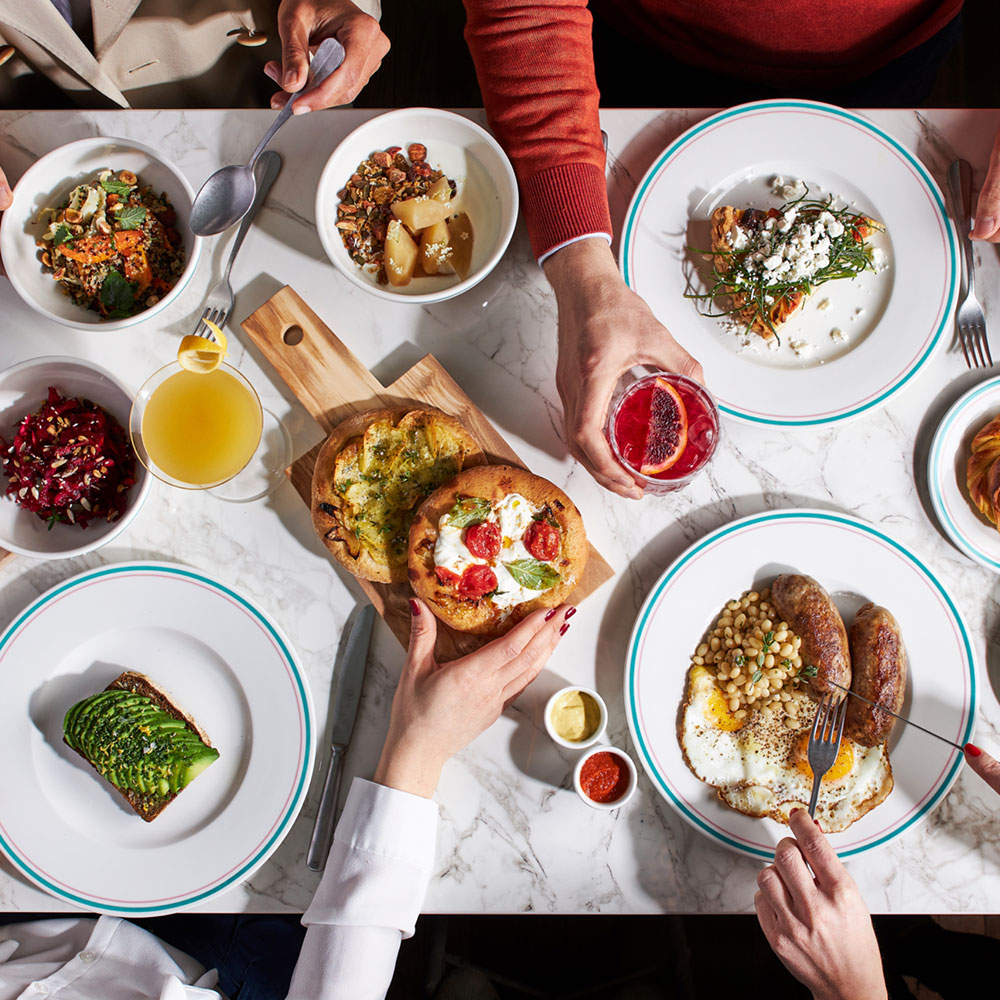 A table shot from above, with people eating multiple plates of colourful food