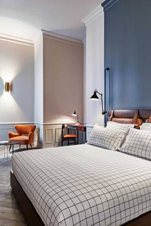 Letto matrimoniale in camera accogliente con pareti blu in hotel a Parigi