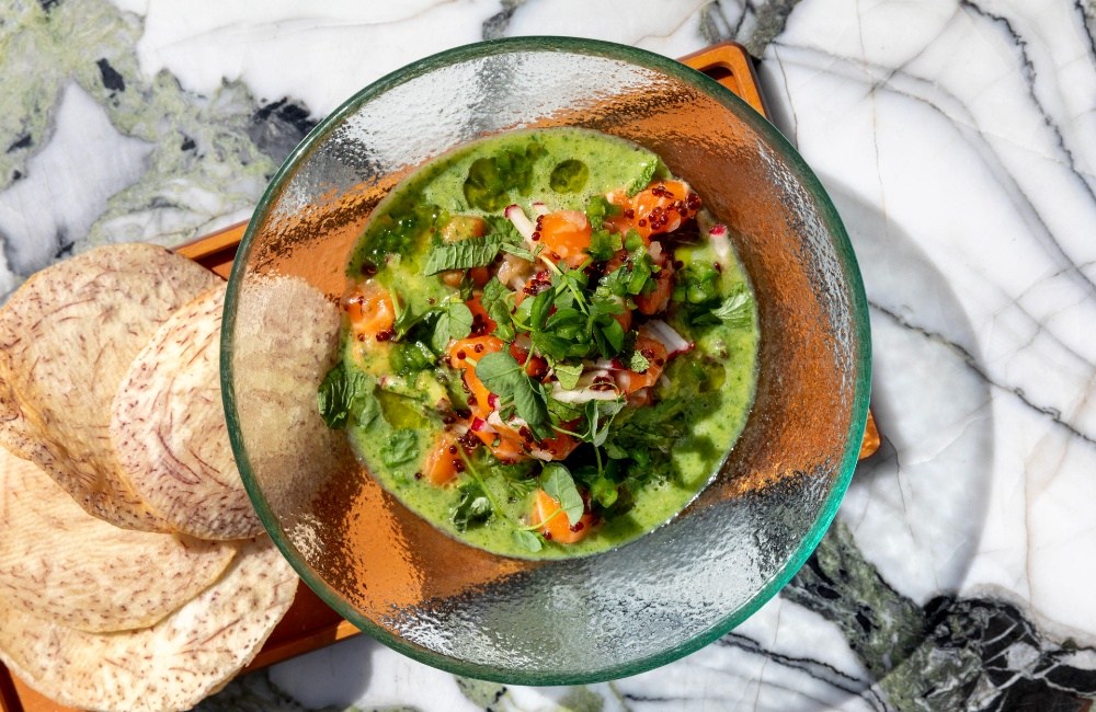 Een gerecht in levendig groen, geserveerd in een diepe, doorzichtige glazen schaal.