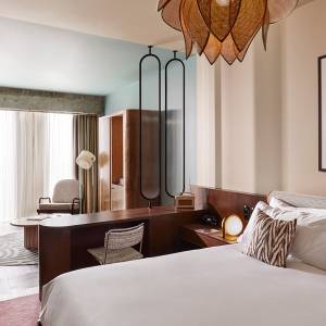 Une chambre d'hôtel avec un grand lit double au premier plan et un coin salon à l'arrière-plan.