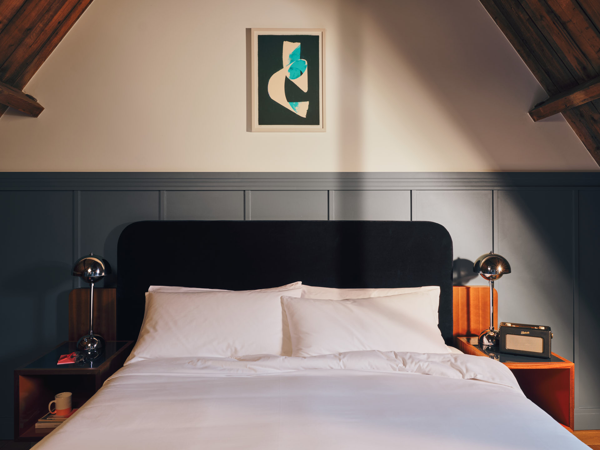 Front view of bed in the Studio room with two pillows and art on the wall