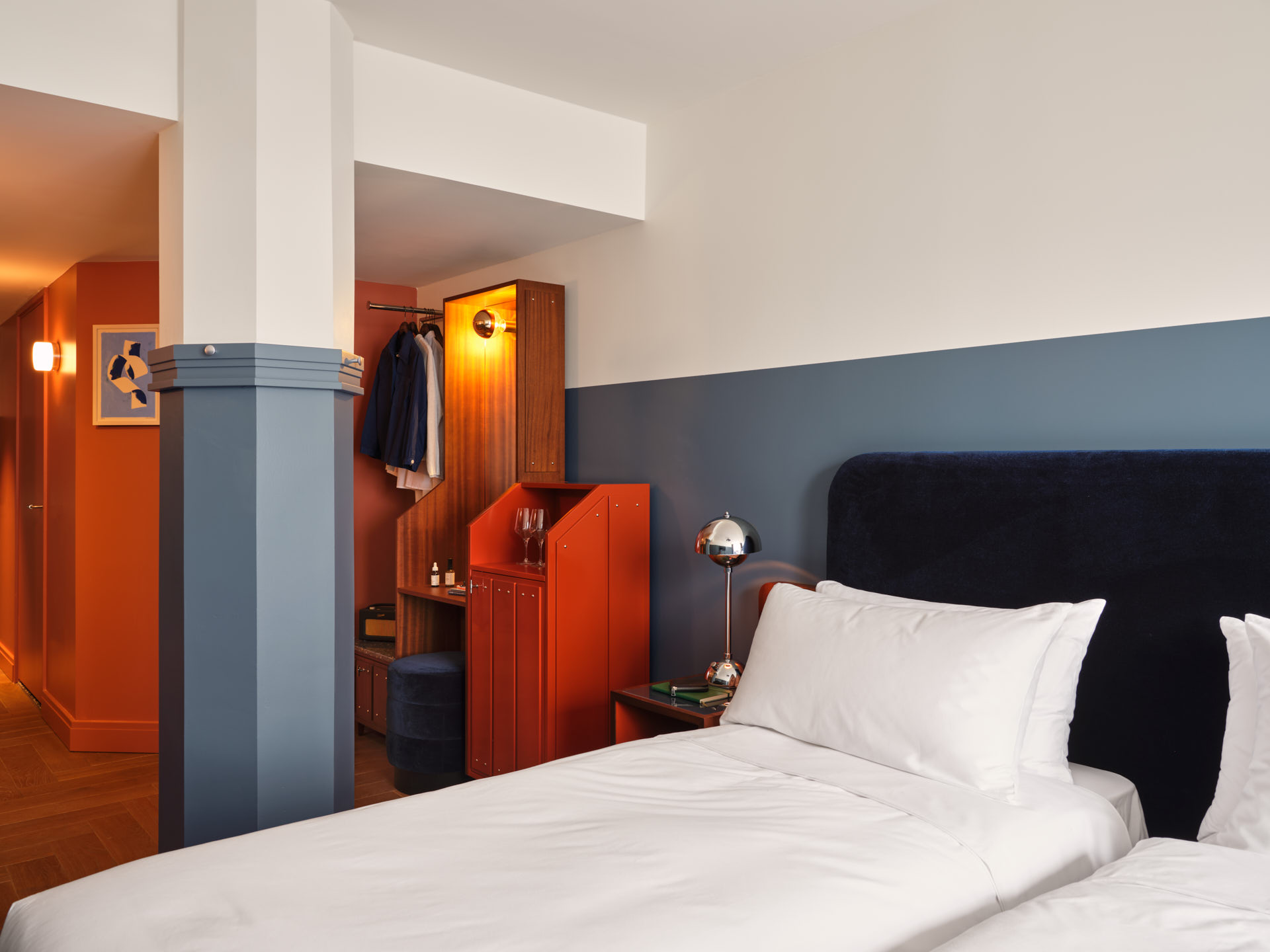 Other twin bed on interior side of the room with ensuite nearby and soft lamp light