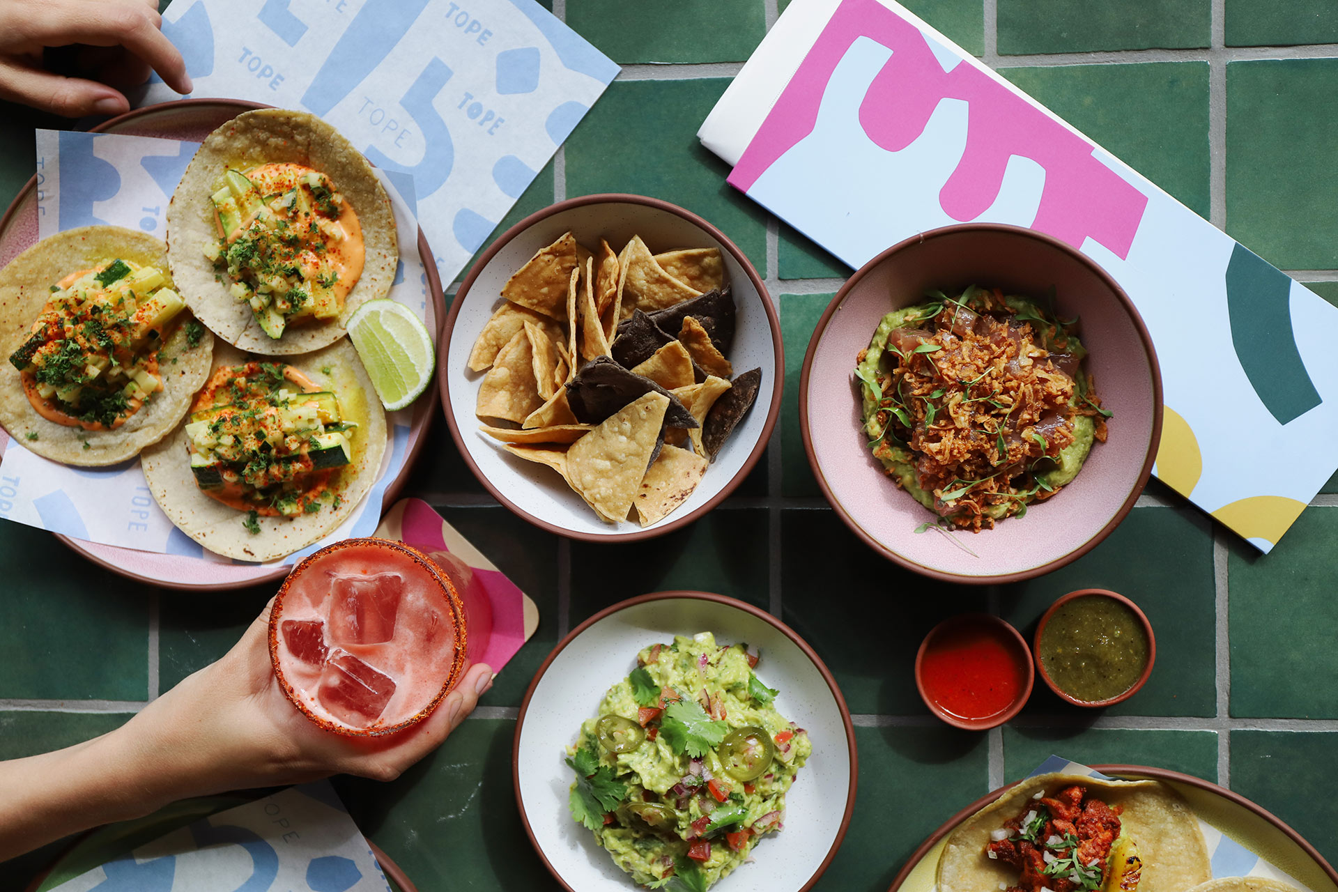 Array of tacos, cocktails, guac and other tasty treats shot from above