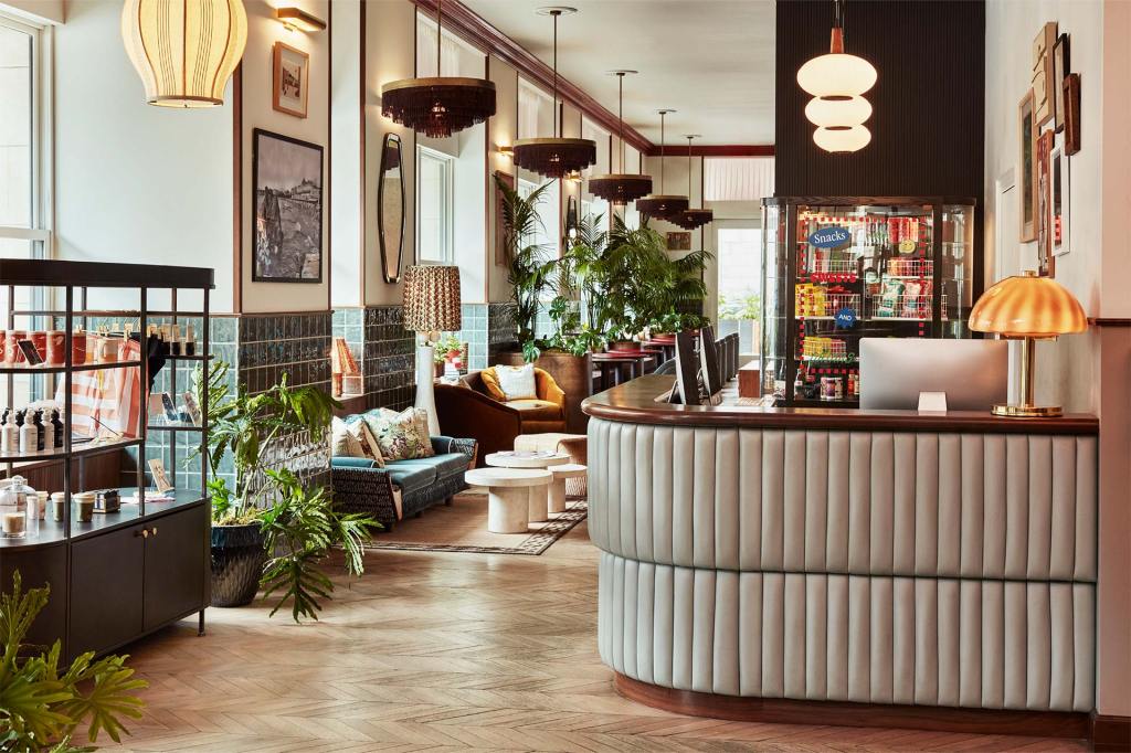 Reception area at Hoxton Downtown LA with wall art, snack fridge and wide windows.