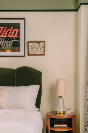 Interno della camera da letto con finestra alta, molte opere d'arte alle pareti e un letto confortevole