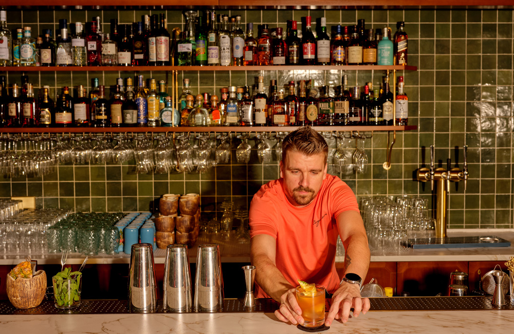 Bartender serving up a cocktail behind the fully stock bar.