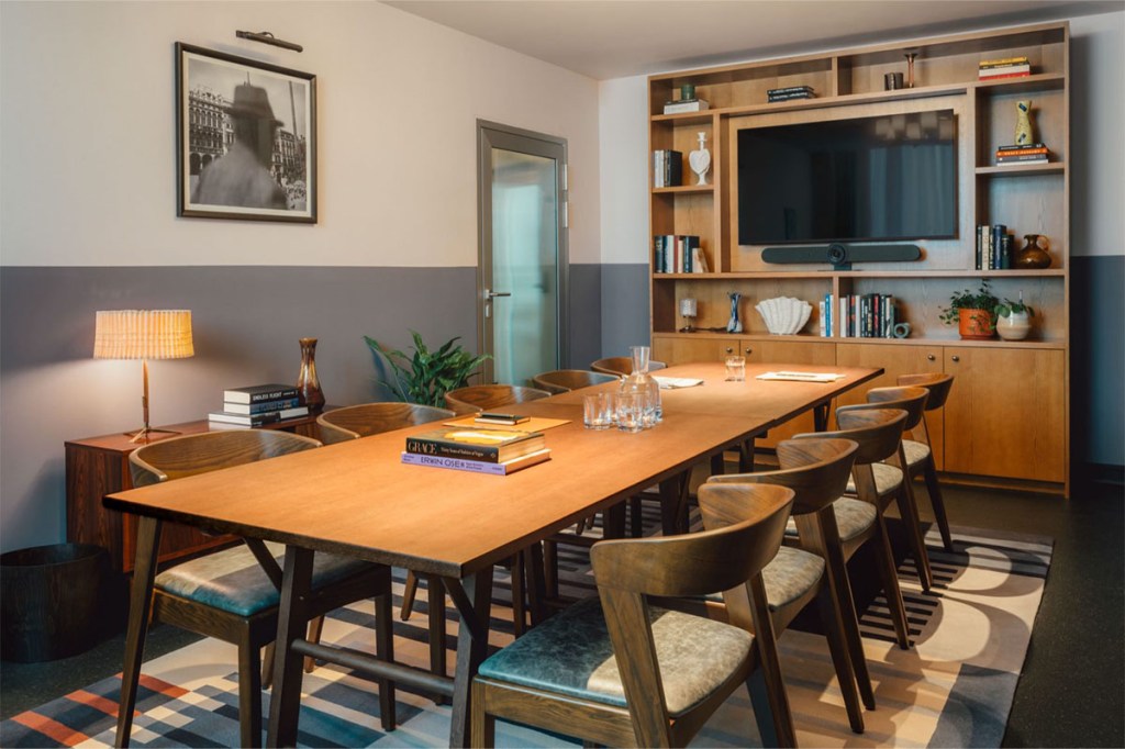 long boardroom table with chairs and tv mounted on the wall.