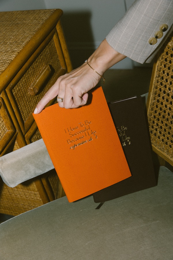 Foto di Nic Ford.Mano che regge un libro arancione brillante. - The Localist, Hoxton Hotels.