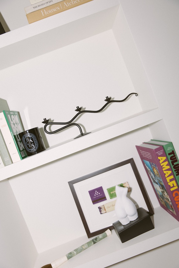 Libreria bianca che espone diversi oggetti, da libri, candelabri, candele profumate e molto altro ancora.- The Localist, Hoxton Hotels.
