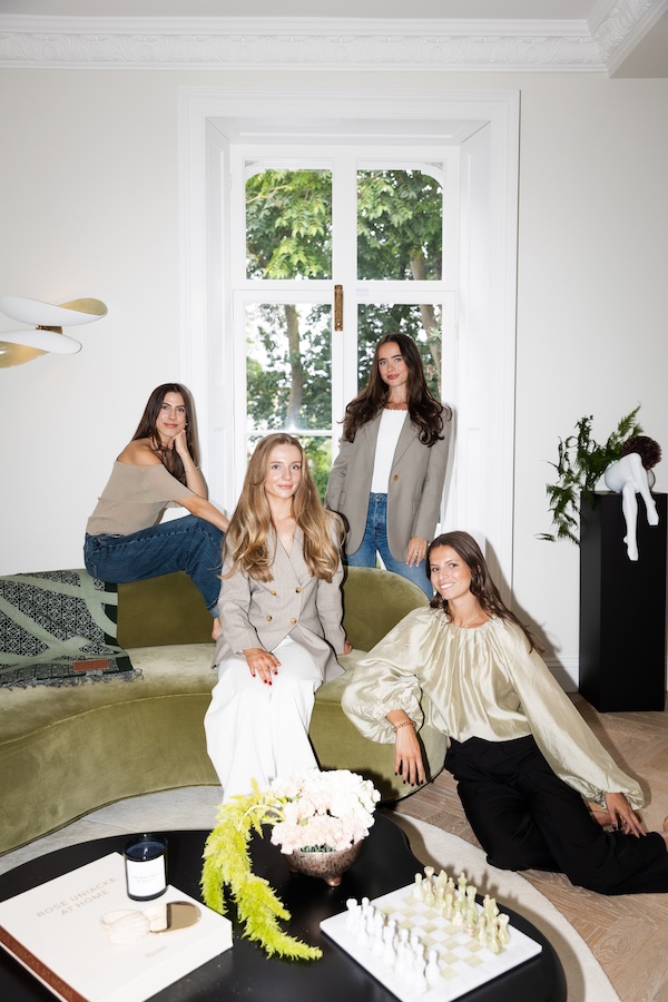 Foto di gruppo di 4 donne intorno a un divano di velluto verde e diversi ornamenti su un tavolino nero - The Localist, Hoxton Hotels.