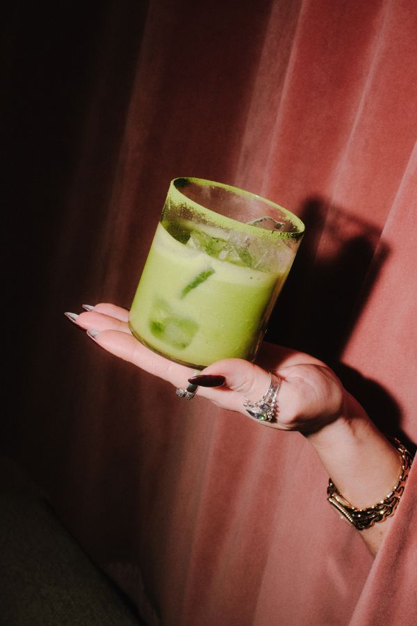 Une main tenant une boisson glacée rafraîchissante au lait vert.